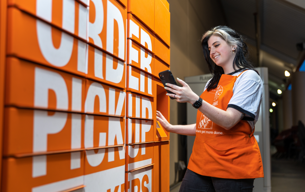 Young white woman with dyed hair smiles as she opens an order pickup locker.