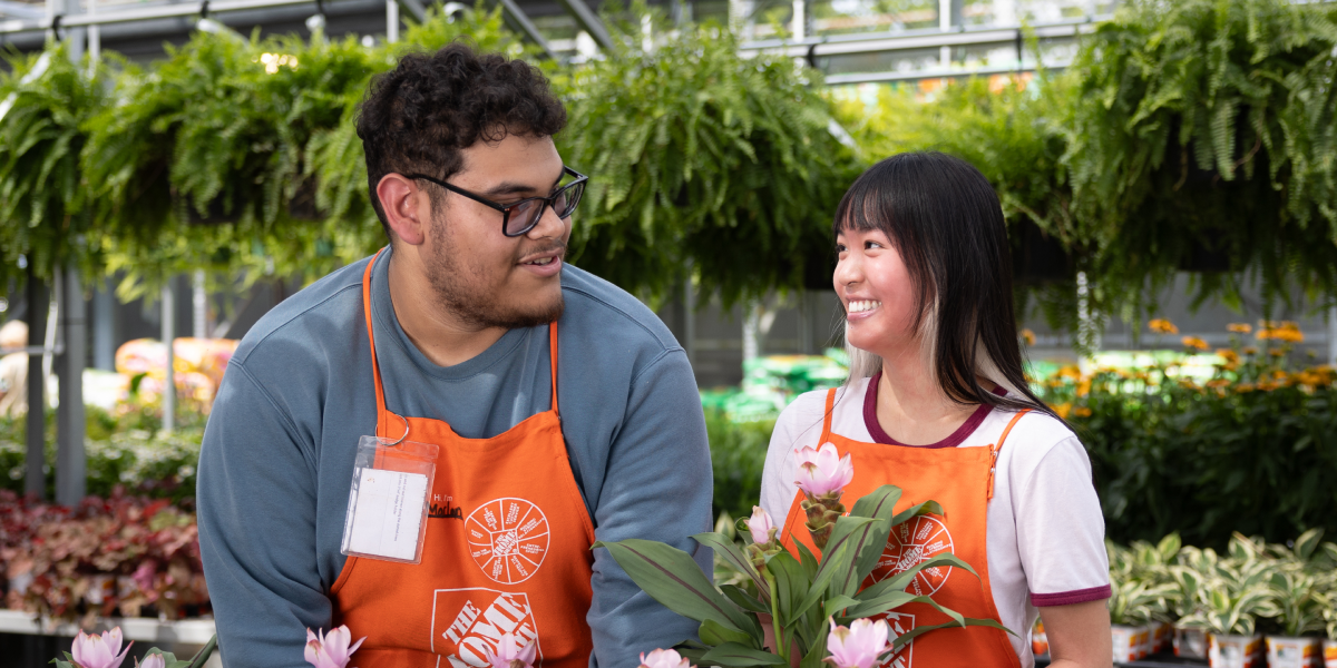 Two Home Depot employees in a garden section smiling