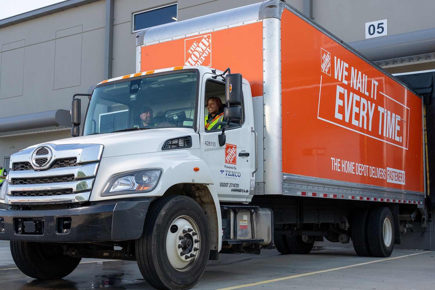 Two associates sitting in a box truck in a warehouse loading area