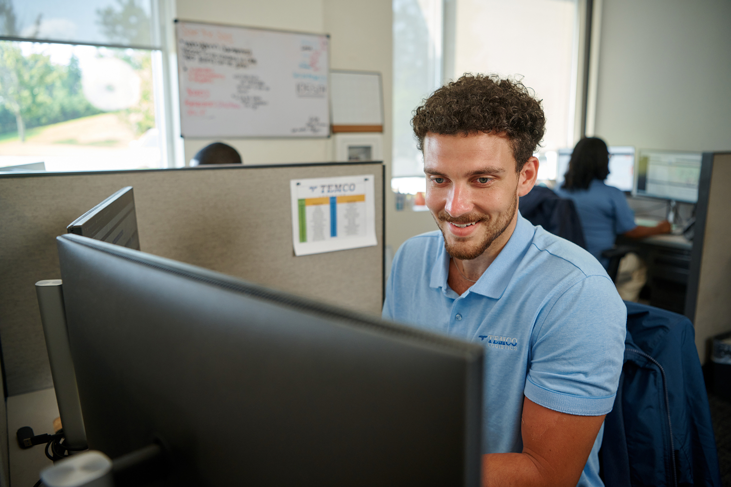 An associate sitting at a desk working on a computer in an office