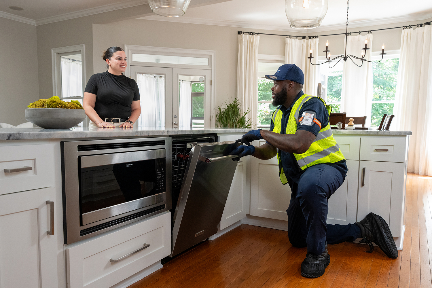 An associate completing a dishwasher installation in a customer's home as they watch