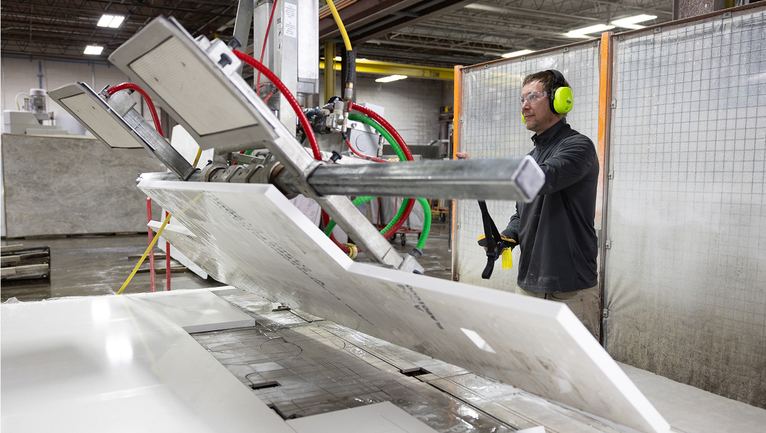 An associate uses a machine to cut marble